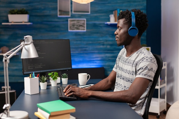 Afroamerikanischer IT-Mitarbeiter mit Headset, der von zu Hause aus arbeitet