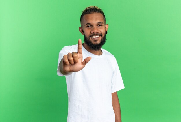 Afroamerikanischer junger Mann im weißen T-Shirt, der mit großem Lächeln in die Kamera schaut