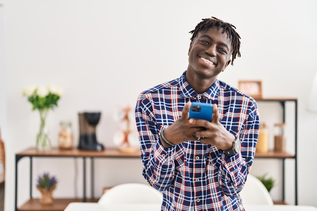 Afroamerikanischer Mann benutzt Smartphone, während er zu Hause steht