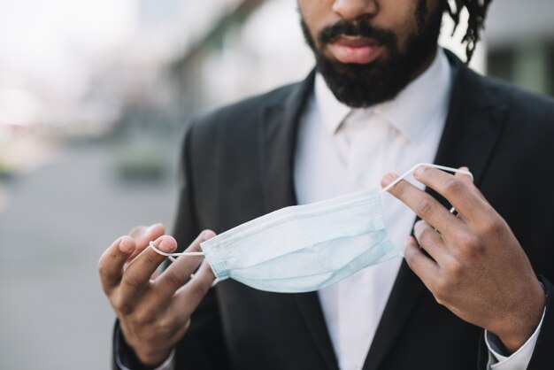 Afroamerikanischer Mann, der medizinische Maske hält