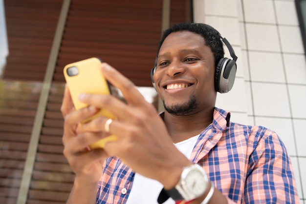 Afroamerikanischer mann, der sein handy benutzt, während er draußen auf der straße steht