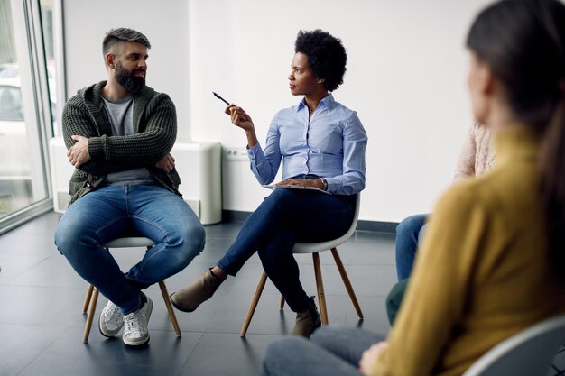 Afroamerikanischer Psychiater im Gespräch mit einem Mann während einer Gruppentherapie