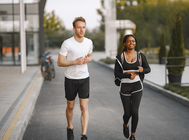 Afroamerikanisches Fitness-Model und kaukasischer Mann, der im Freien joggt