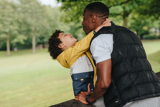 Afroamerikanisches Kind und sein Vater spielen im Park