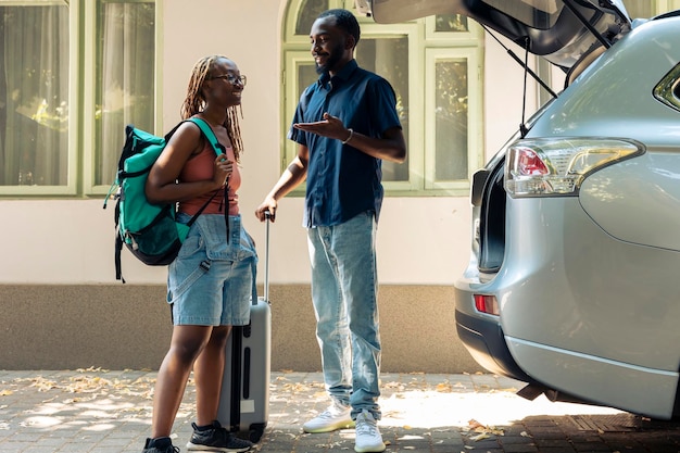 Afroamerikanisches Paar, das mit dem Auto reist, Gepäck und Gepäck in den Kofferraum legt, um in den Sommerurlaub zu fahren. Menschen in Beziehung, die mit Trolley und Reisetaschen auf Urlaubsreise gehen.