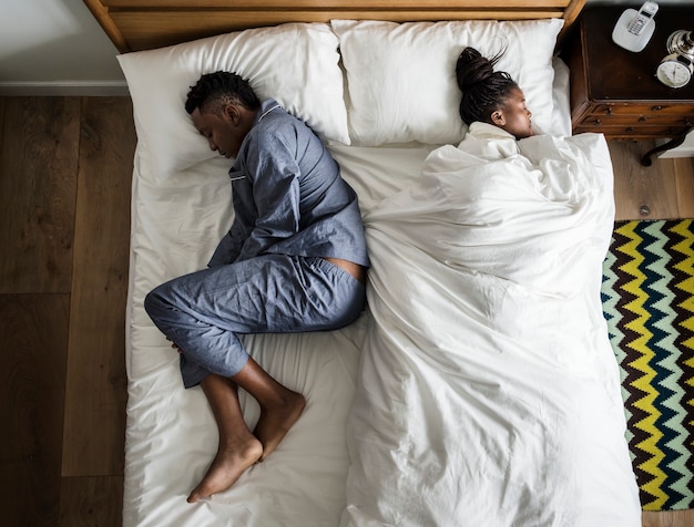 Afroamerikanisches Paar, das Rücken an Rücken schläft