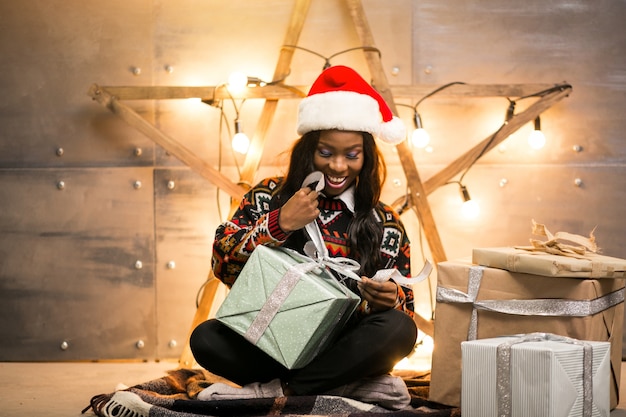 Afroe-amerikanisch Frau, die Weihnachtsgeschenke auspackt