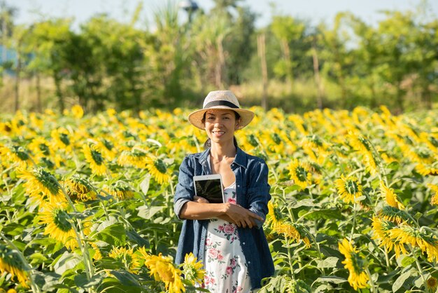 Agronom mit einer Tablette in der Hand arbeitet im Feld mit Sonnenblumen. Online-Verkäufe tätigen. das mädchen arbeitet im feld und analysiert das wachstum der pflanzenkultur. Moderne Technologie. landwirtschaftliches Konzept.