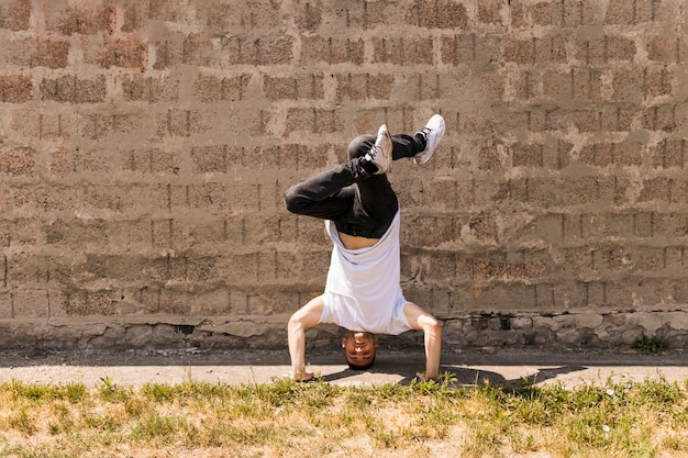 Akrobatisches Breakdancetänzer des Hip-Hop gegen Wand