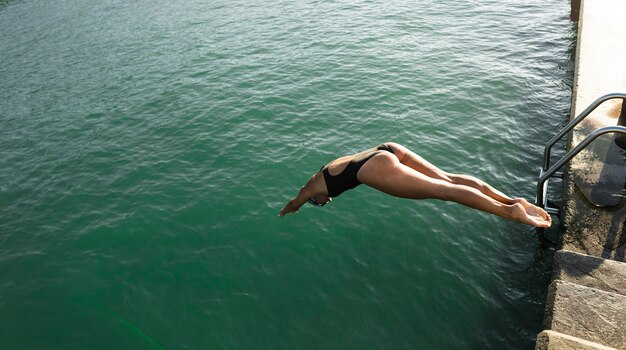 Aktive junge Frau, die in das Wasser springt