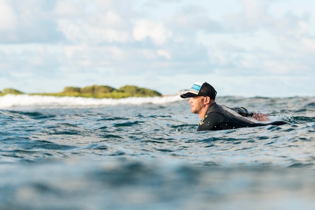 Kostenloses Foto aktiver mann in spezialausrüstung, der auf einem surfbrett bleibt staying