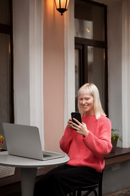 Albino-Frau mit mittlerem Schuss, die mit Laptop arbeitet