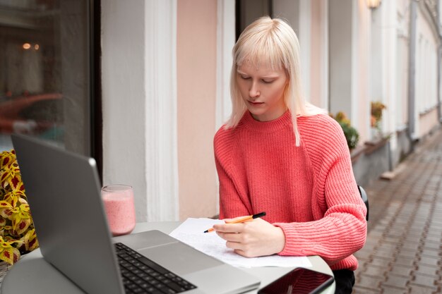 Albino-Frau mit mittlerem Schuss, die mit Laptop arbeitet