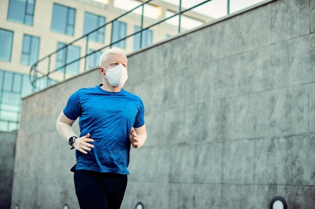 Albino-Sportler mit schützender Gesichtsmaske beim Joggen in der Stadt