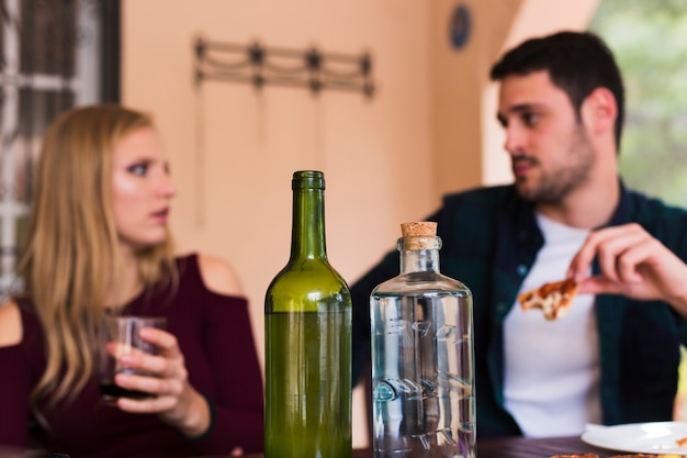 Alkoholflasche vor den Paaren, die Lebensmittel essen