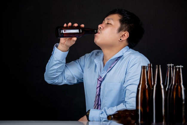 Alkoholischer asiatischer mann mit vielen bierflaschen