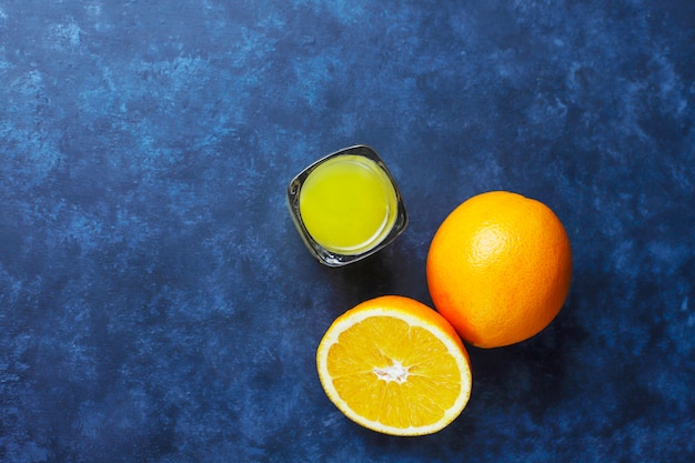 Alkoholisches Orangensaftgetränk im Schnapsglas mit orange Scheibe und Orange auf dunklem Hintergrund