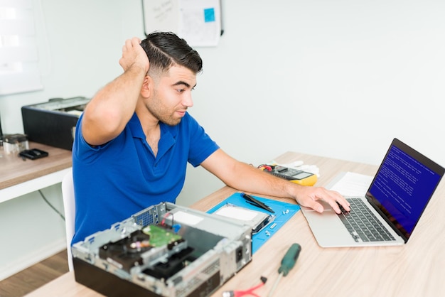 Alles ging schief. Besorgter lateinamerikanischer Techniker weiß nicht, wie er die Laptop-Software in der Reparaturwerkstatt reparieren kann