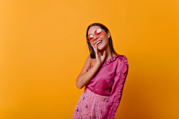 Alm Frau in rosa Top mit Rüschen Posen, zeigt Freude. Foto des Modells mit nacktem Make-up in gemütlicher Atmosphäre