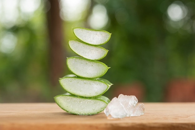 Aloe vera auf produktdisplay holz zähler hintergrund. aloe vera ist eine tropische grünpflanze. geschnittene aloe vera natürliche organische erneuerungskosmetik, alternative medizin. bio-hautpflegekonzept.