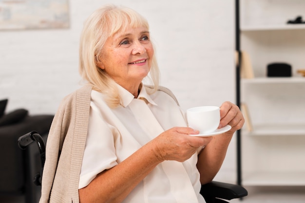 Alte Frau, die eine Tasse Tee hält