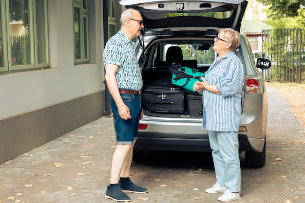 Kostenloses Foto alte menschen, die in den urlaub fahren, koffer und gepäck zu hause in den kofferraum laden. reisen sie mit dem auto mit gepäck und taschen und verlassen sie die abenteuerreise durch das stadtbild von onubran.