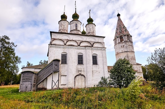 Alte orthodoxe Kirche im Dorf. Sommeransicht mit Blumenwiese. Sonniger Tag, blauer Himmel mit Wolken.