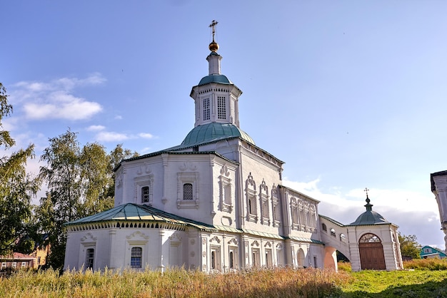 Alte orthodoxe Kirche im Dorf. Sommeransicht mit Blumenwiese. Sonniger Tag, blauer Himmel mit Wolken.