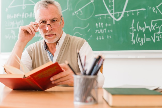 Kostenloses Foto alter lehrer, der in der schule kamera betrachtet