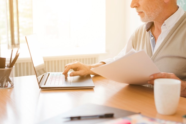 Alter Mann, der am Laptop arbeitet