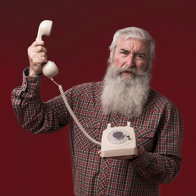 Alter Mann, der ein Telefon hält