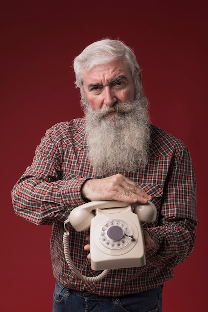 Alter Mann, der ein Telefon hält