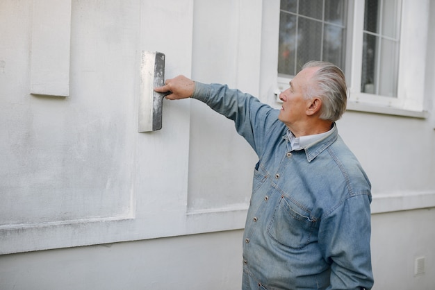 Alter Mann, der nahes Gebäude mit Werkzeugen einer Reparatur steht