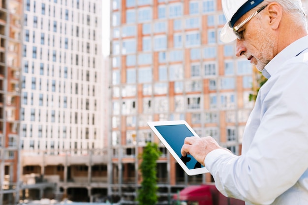 Alter Mann der Seitenansicht, der eine Tablette betrachtet