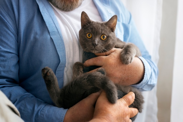 Alter Mann der Vorderansicht, der Katze hält