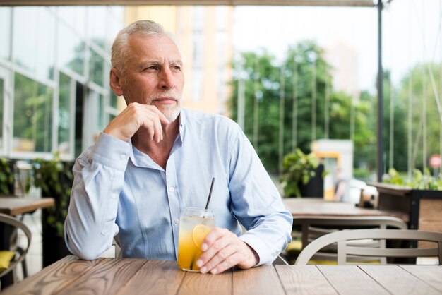 Kostenloses Foto alter mann des mittleren schusses, der am restaurant denkt