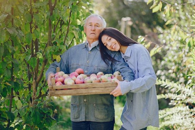 Alter Senior, der in einem Sommergarten mit Ernte steht