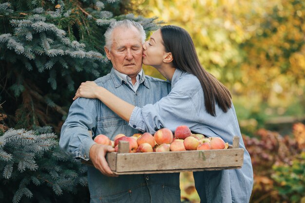 Alter Senior, der in einem Sommergarten mit Ernte steht