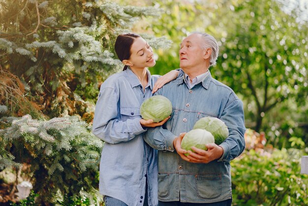 Alter Senior, der in einem Sommergarten mit Kohl steht