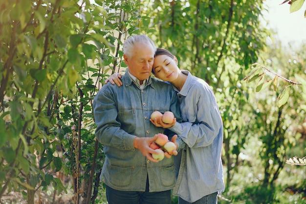 Alter Senior, der in einem Sommergarten mit Äpfeln steht