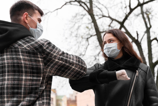 Kostenloses Foto alternative grüße mit ellbogenstoß und tragen von masken