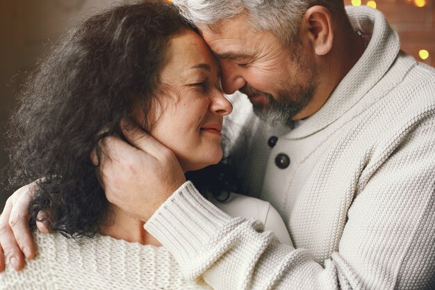 Alters- und Personenkonzept. Älteres Paar mit Geschenkbox über Lichthintergrund. Frau in einem weißen Strickpullover.