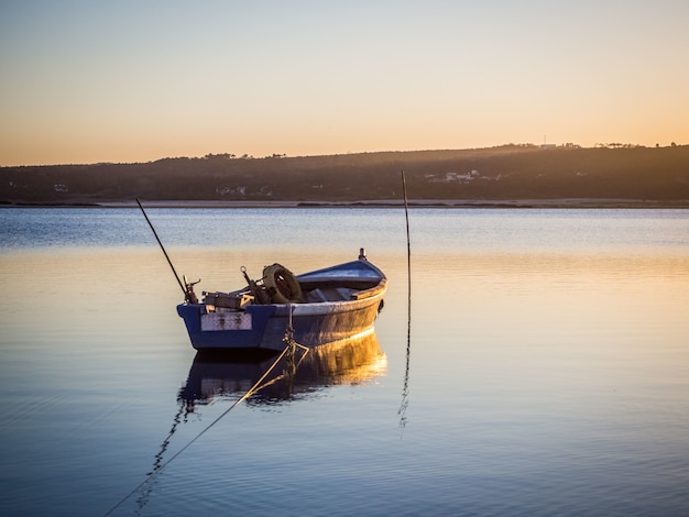 Altes Fischerboot am Fluss mit dem atemberaubenden Blick auf den Sonnenuntergang