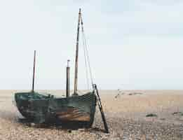 Kostenloses Foto altes holzboot auf dem sand hinter einer frau