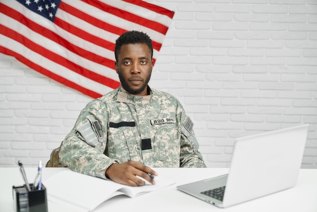 Amerikanischer Soldat sitzt auf dem Tisch und sieht sich Dokumente an