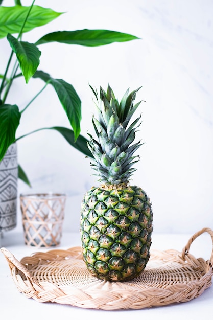 Ananas in gewebtem Bambusteller auf weißem Tisch