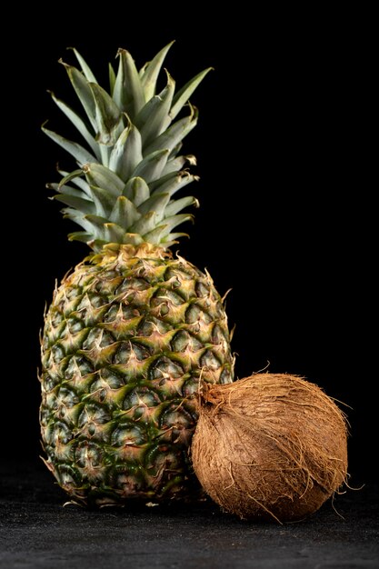 Ananas-Kokos frische frische reife Früchte lokalisiert auf dunklem Boden