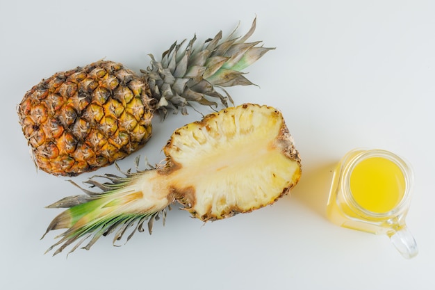 Ananas mit Saft auf weißer Oberfläche