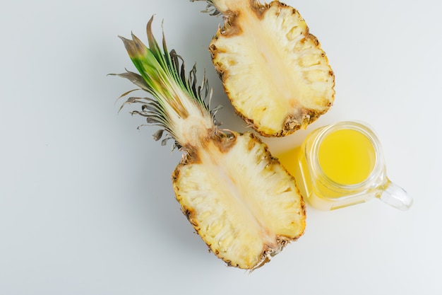 Ananas mit Saft auf weißer Oberfläche