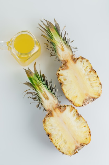 Ananas mit Saft auf weißer Oberfläche